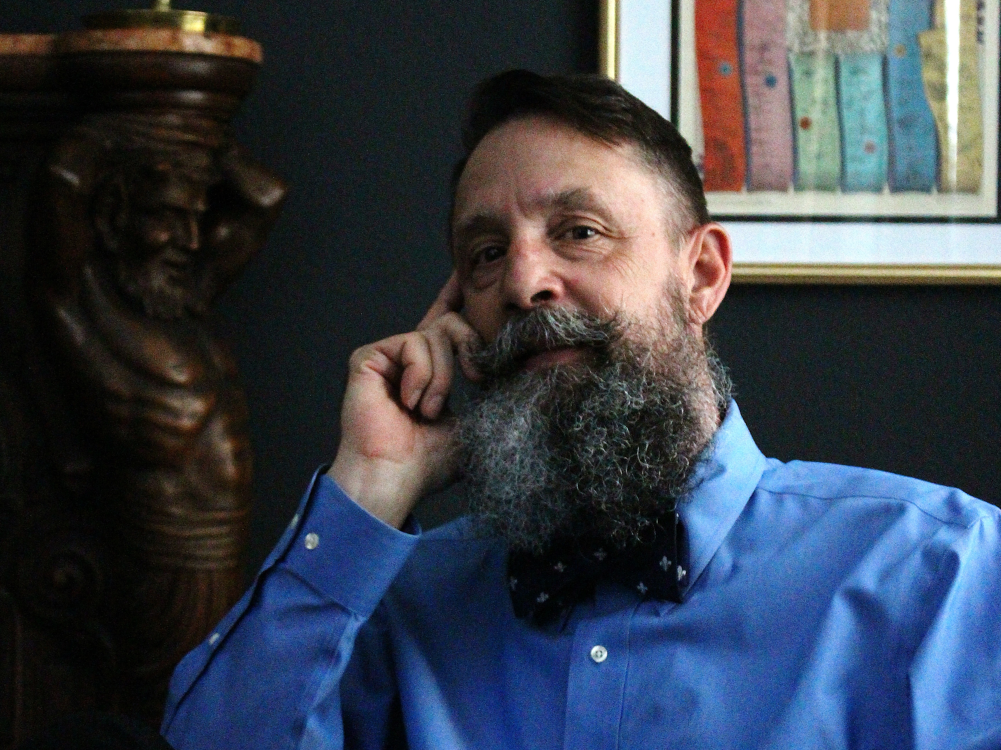 Shane Meche reading beside a curtained window